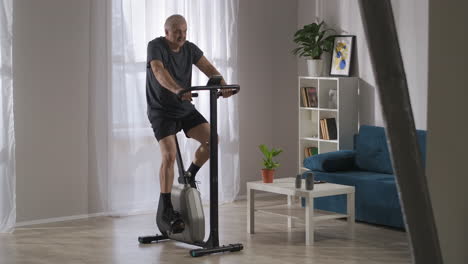 Sportliche-Aktivität-Zu-Hause-Mann-Mittleren-Alters-Nutzt-Stationäres-Fahrrad-Im-Wohnzimmer-Gesunder-Lebensstil-Für-Menschen-In-Selbstisolation